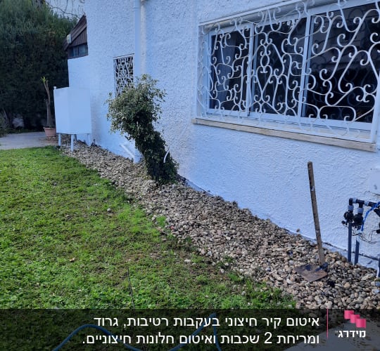 צינור מים כחול על דשא ליד קיר לבן
